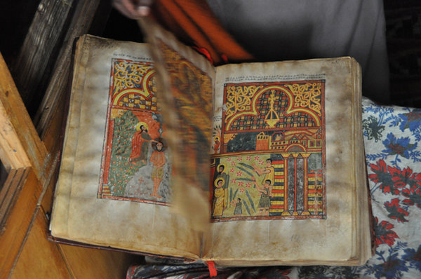A monk turns the pages of an 800 year old book - Lake Tana