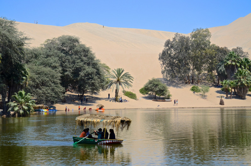 Huacachina lagoon with the great sand dunes hovering above