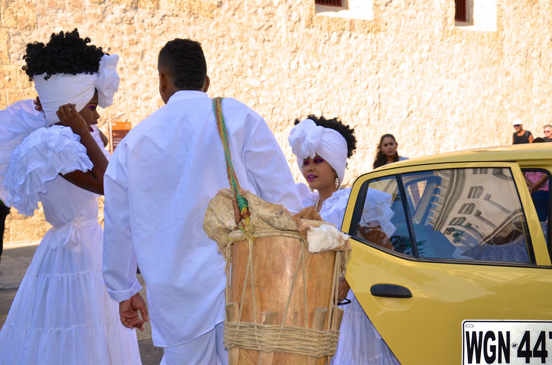Wedding celebrants with drums climb out of a tiny car 