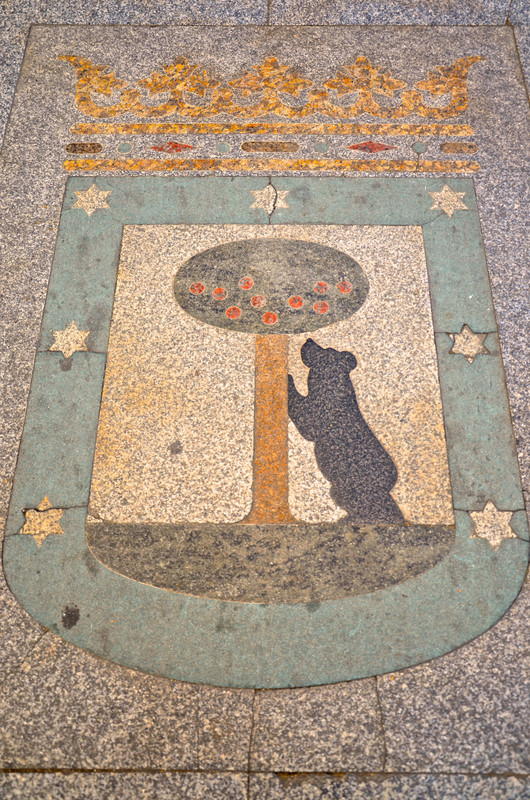 Madrid’s famous coat of arms, a statue of a bear and a strawberry tree in the pavement