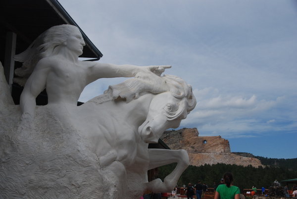 Sculpture of Crazy Horse with monument in the background