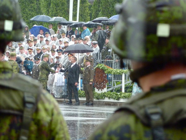 The President of Estonia (center) and crowds in the stands celebrate Victory Day in the pouring rain in Parnu 