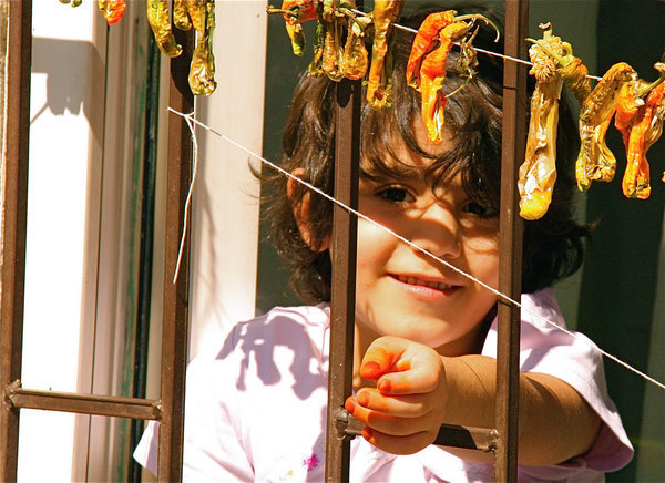 Girl peering from window with dried peppers, Ankara Castle Slum