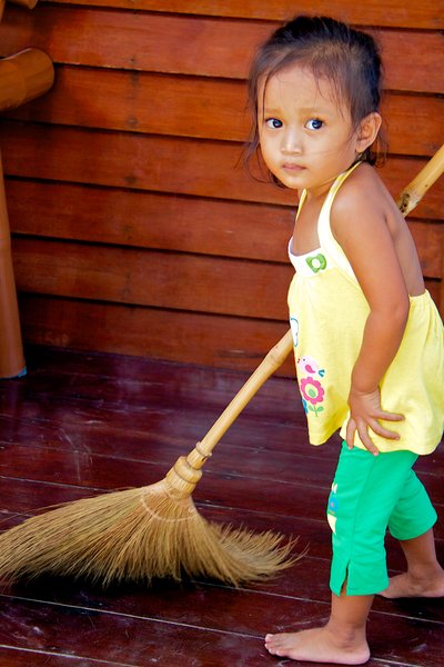 Young girl helping mom sweep the beach hotel