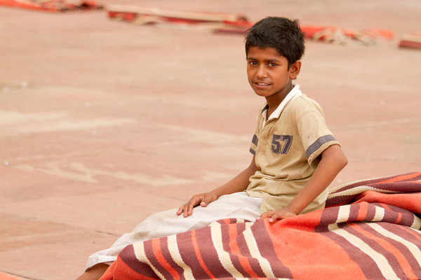Boy takes a break from setting out prayer mats, Jama Masjid