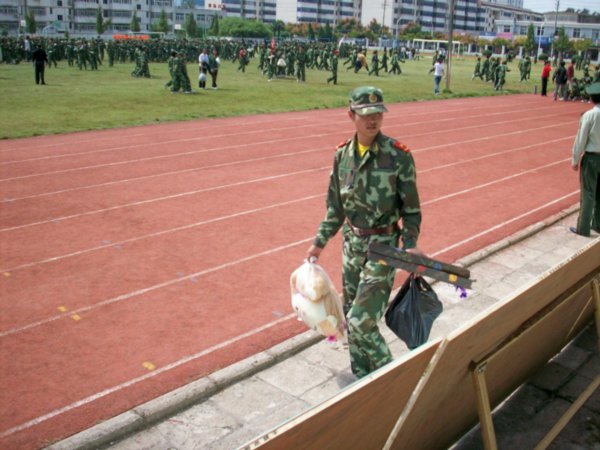 A soldier is never comfortable, having to carry a stuffed animal.