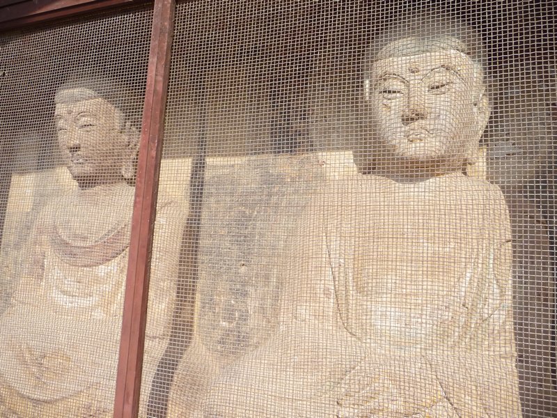 Despite the screen, the serene faces of the Buddha smile toward the visitors.