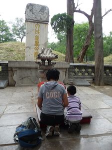 Praying in front of the simple tomb-mount of Confucius.