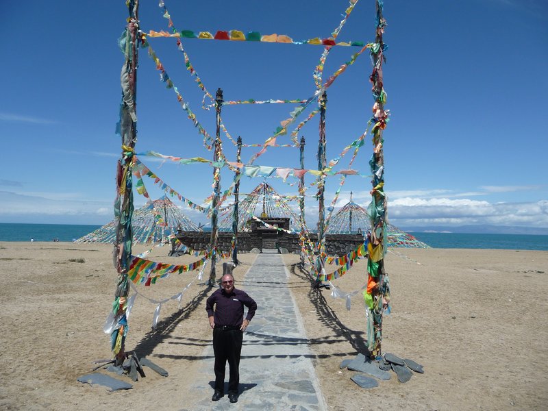 A small board-walk, covered in Tibetan prayer flags, leads to an altar along the shores of Qinghai Lake.