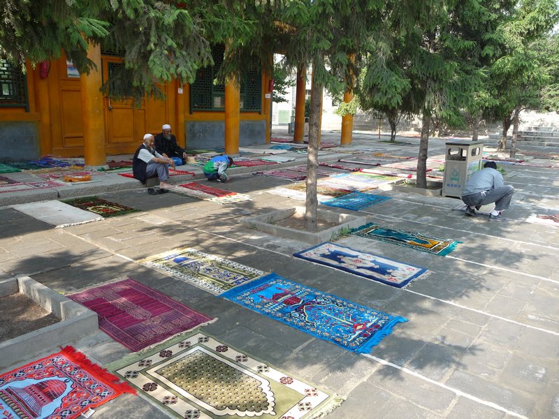 Prayer-rugs of the Muslim faithful begin to crowd the courtyard of the Great Mosque in Xining.