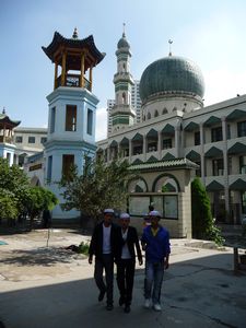 Young men walk in the courtyard. Note the dome of the mosque, the tall new minaret, and the ancient, Chinese-style minaret from the 14th Century.