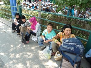 The trees along the streets provide minimal shade for the women and the children. 