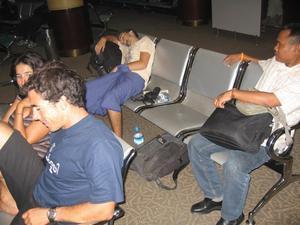 Brian, (also wearing his longyi for the flight home), sleeps in the airport after a big last night out.