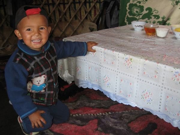 Islan's little brother at the table, inside the yurt