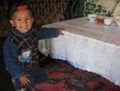 Islan's little brother at the table, inside the yurt