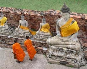 Monks walk along a long line of Buddhas, (Ayuthaya)