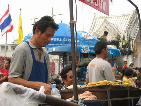 Street vendor selling kebabs, manned tank in background