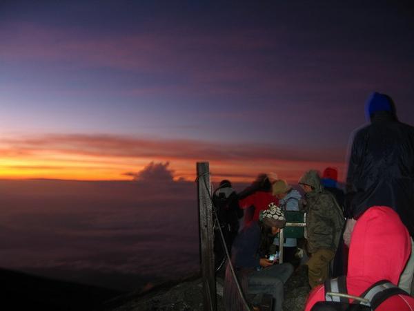 Fellow climbers huddle together at the summit, awaiting the dawn