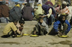 Beggars comiendo en las escaleras del ghat, entre ellos algunos niños. La comida es gratuita, la hacen con los aportes de la caridad pública.