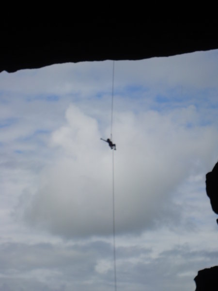 Someone rappelling down he mouth of the cave.