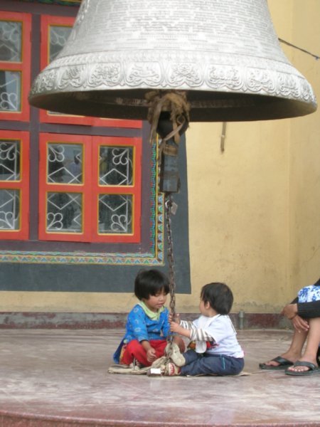 Children playing under a huge engraved bell.