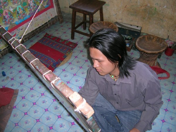Sonam Lama at work, on the floor of course with the canvas attached by a string to the wall. That way they can use the light wherever it may be.
