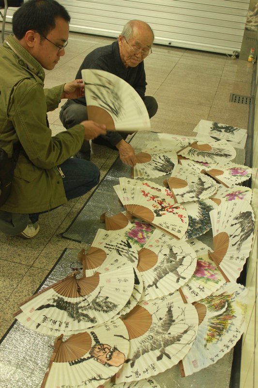 old man selling own-made fans at the subway