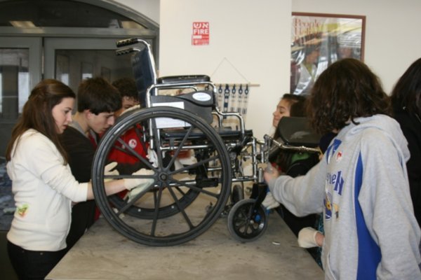 The kids clean a wheelchair for Yad Sarah