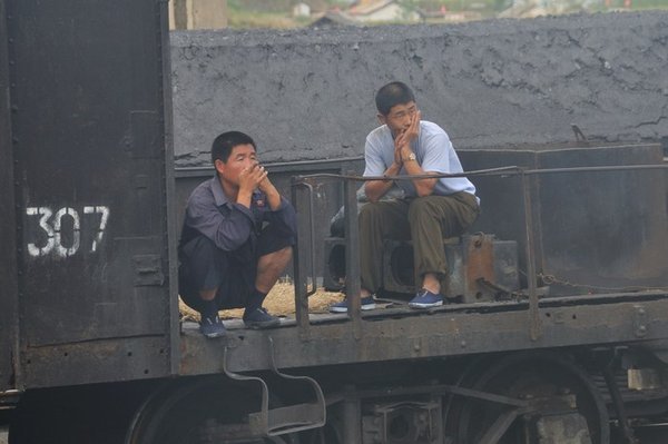 Listless workers pass the time at a North Korean train station