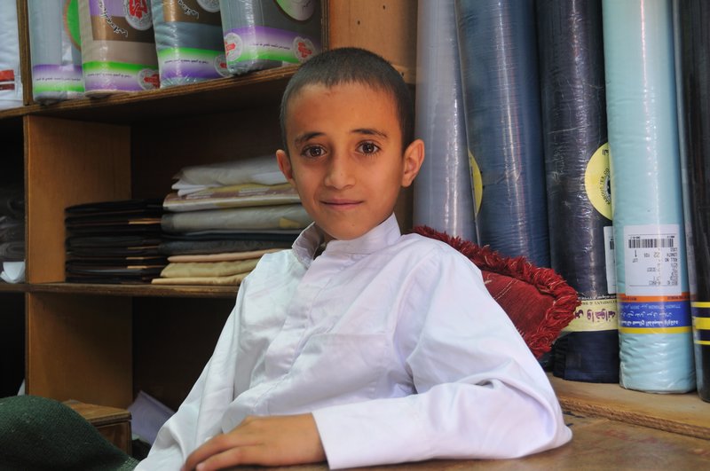 Boy working in father's tailor store - Yemen, Sana'a