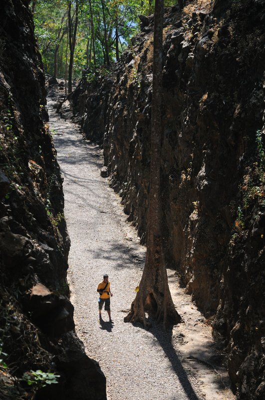 Lone figure walks through Konyu Cutting - Hellffire Pass Memorial, near Kanchanaburi, Thailand 