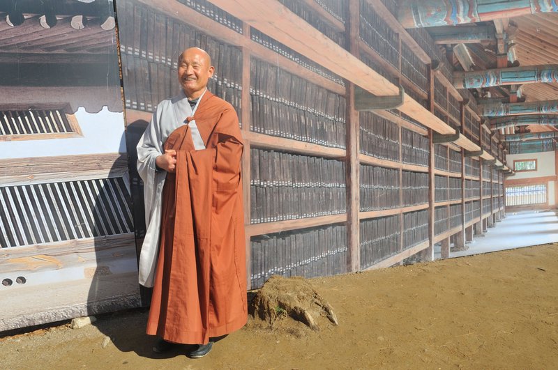 Smiling monk poses in front of Tripitaka Koreana photograph - Haeinsa Temple, near Daegu, South Korea