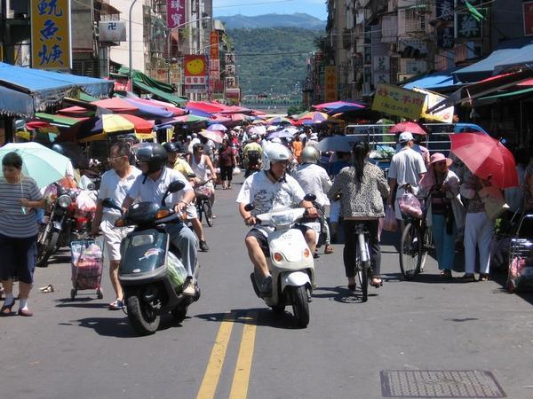 Many scooters in a street market = a quality place to shop!