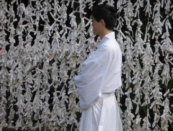 Wedding official waits by a wall of paper prayers - Tsurugaoka Hachiman-gu, Kamakura
