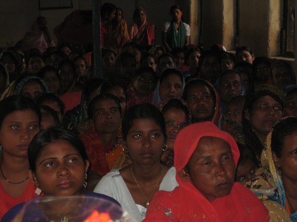 A hundred women listening to Womens Day Program