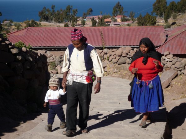Quechafolket på Taquile Island i Titicacasjøen. Vi kan se at han er gift fordi han har mønster på lua helt opp. Legg merke til at kvinnen spinner ulltråd mens hun går