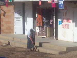 Lady sweeping in front of her store.