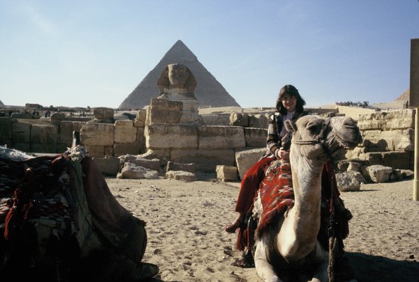 Linda on a camel in front of the Sphinx and a pyramid