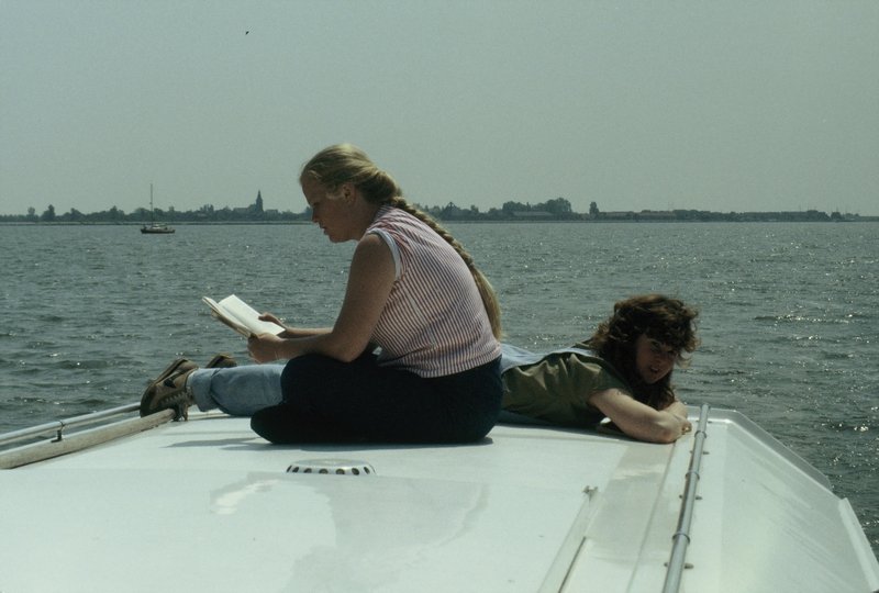 Carol reads while Linda relaxes on deck while crossing the Ijmeer