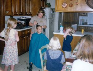 Graham getting his haircut by a neighbor while his cousins watch