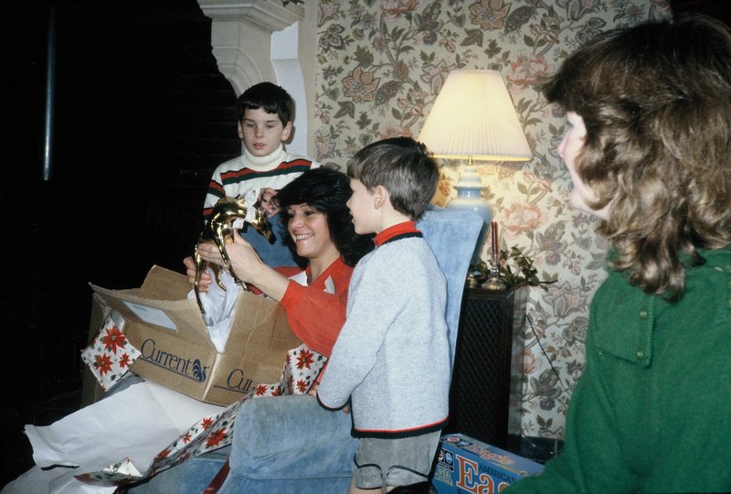 Linda W opening her present while Brit and Parrish and Linda look on