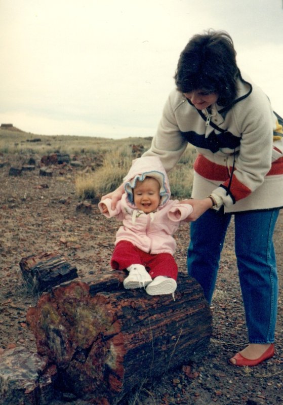 Linda holding Tamara on a petrified log at Petrified Forest National Park