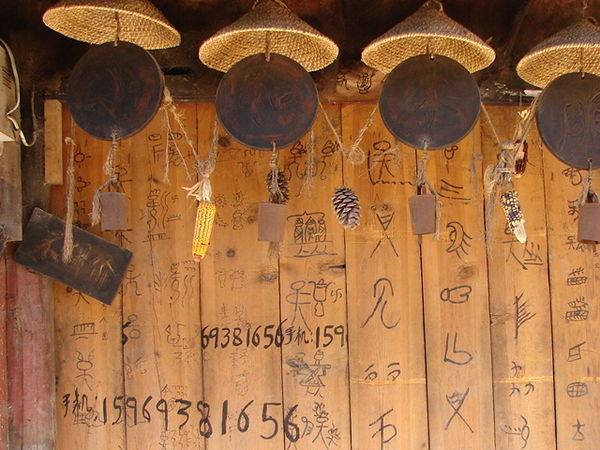Door in Shigu village.  Note the chimes and Naxi pictographs