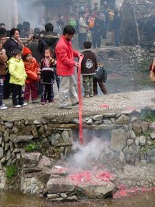 Dit is het voorbeeld dat de kinderen zien: man met een enorme rol brandende firecrackers in de hand ter ere van de trouwers.