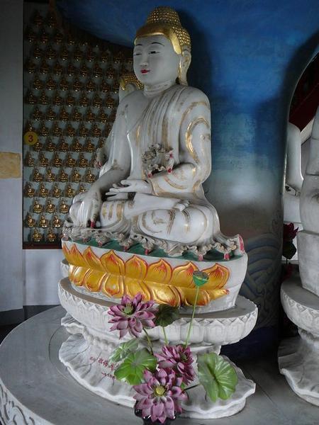 Een grote Boeddha van jade met er achter gesponsorde kleintjes van verguld blik.