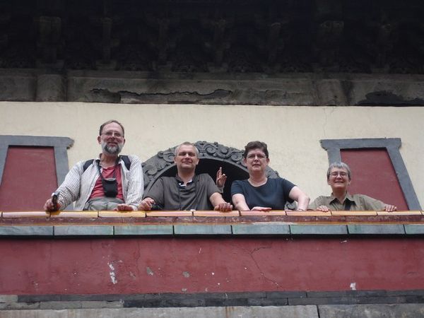 Vier buitenlandse toeristen hebben eindelijk het balkon vrij voor de foto. Toch niet helemaal, een Chinese arm wuift mee op de foto.