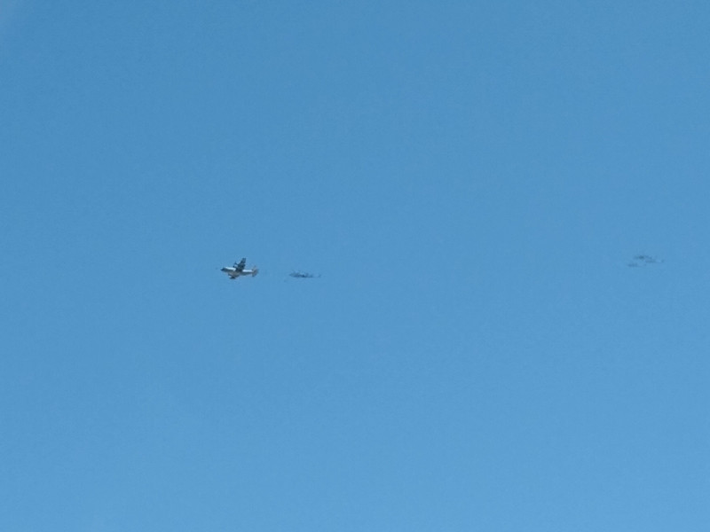 Strange sight:  large, slow plane trailing a white ball, followed closely by two helicopters