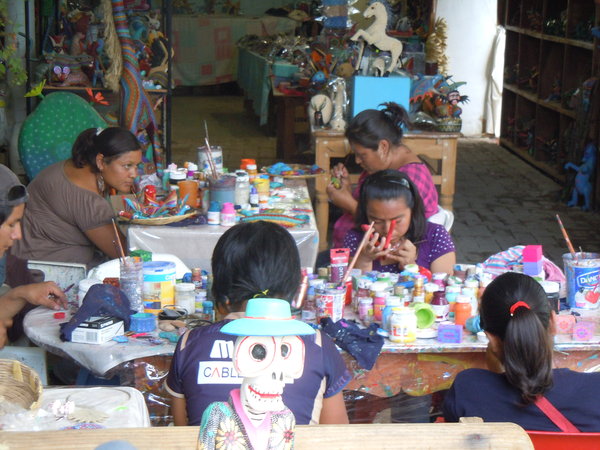Kids in wood carving workshop painting the figures