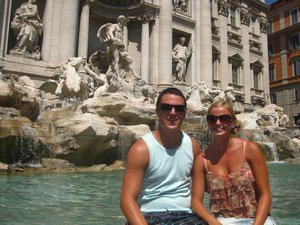 Tanned couple posing next to the Trevi