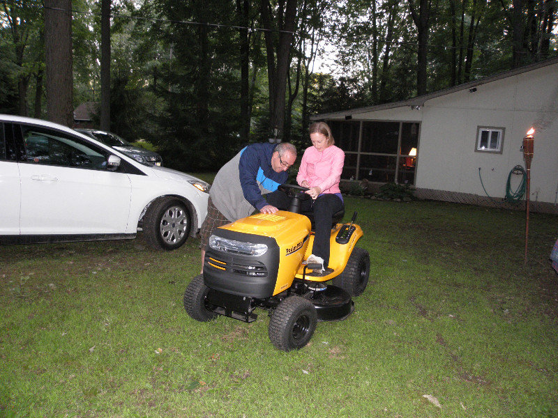 Gus showing Kim how to work the riding lawnmower
